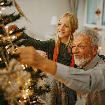 Senior Mann und Enkelin schmücken Weihnachtsbaum