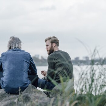 Vater und Sohn im Gespraech an einem Fluss