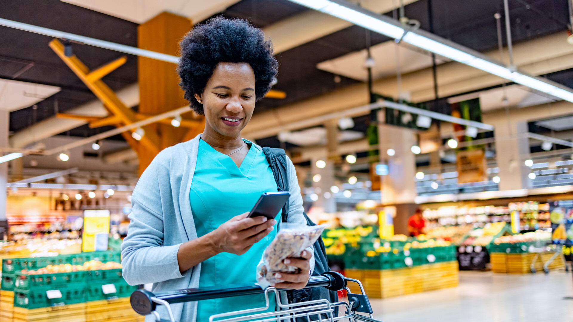 Frau im Supermarkt Frau im Supermarkt schaut auf Handy