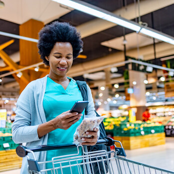 Frau im Supermarkt schaut auf Handy