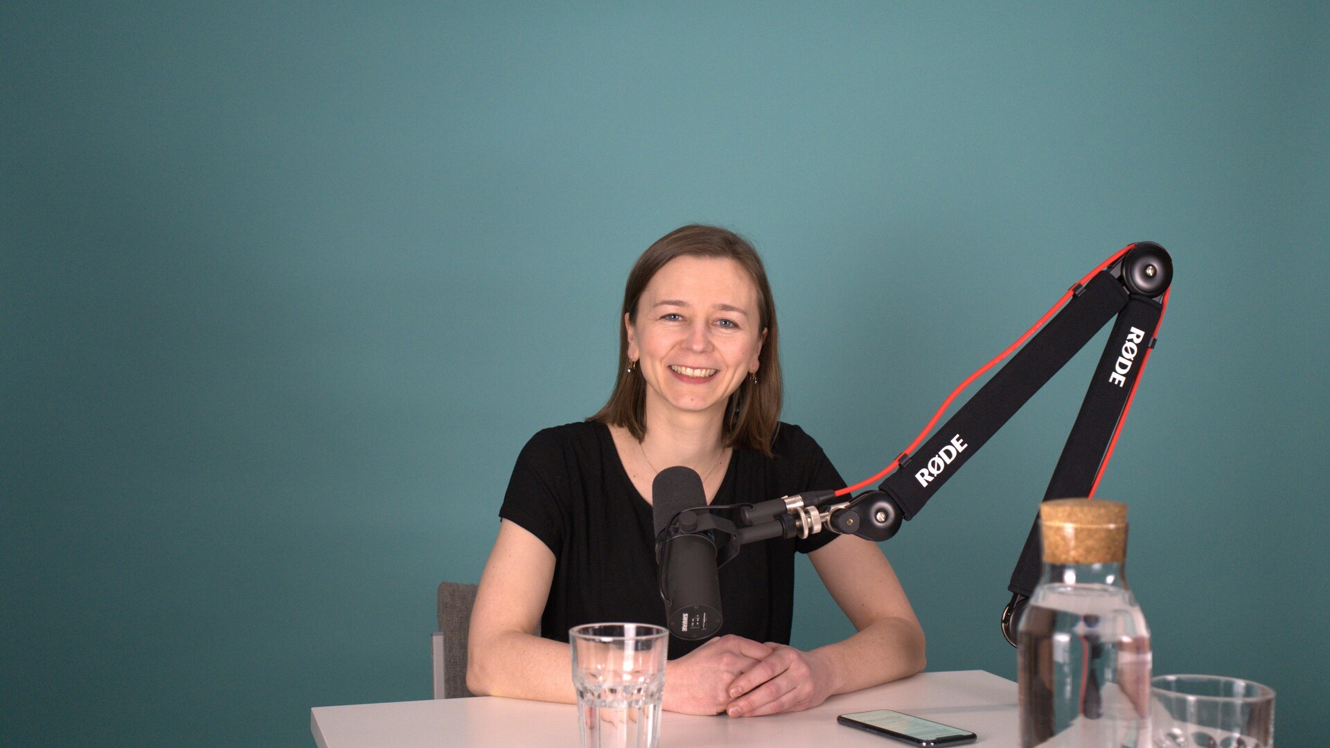 Bild von Carolin Schoppe bei der Podcastaufnahme vor einem mintfarbenen Hintergrund