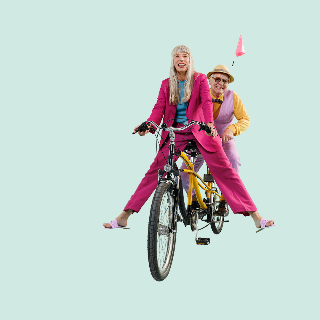 Zwei Menschen fahren auf einem Tandem in bunter Kleidung