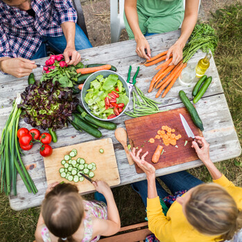 Menschen sitzen an einem gedeckten Tisch mit Gemüse
