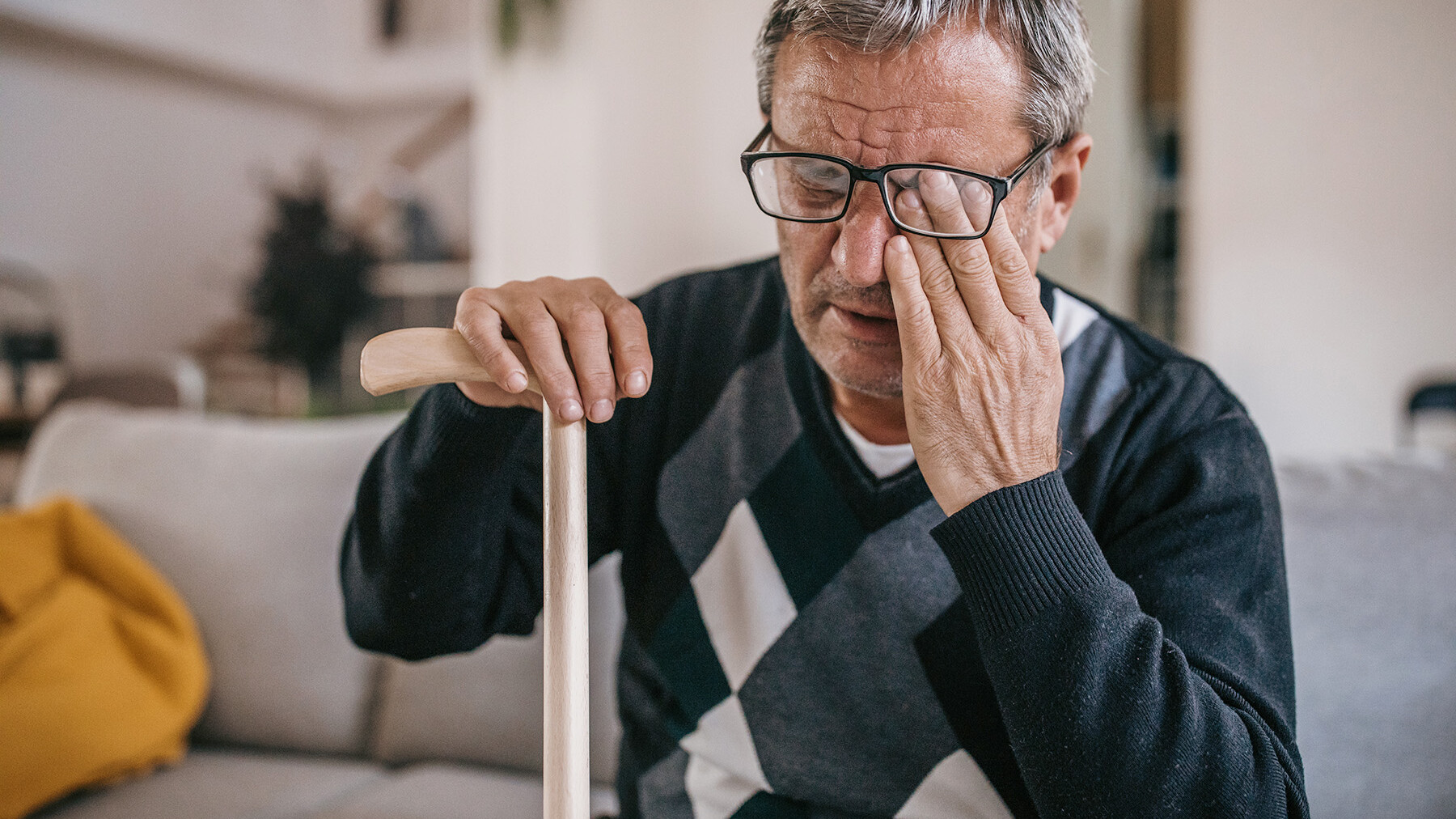 Aelterer Mann reibt sich ein Auge hinter der Brille