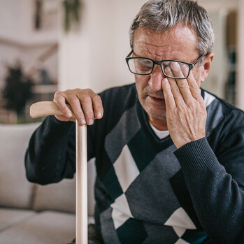 Aelterer Mann reibt sich ein Auge hinter der Brille