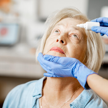 Bild på kvinna som får ögondroppar av sjuksköterska