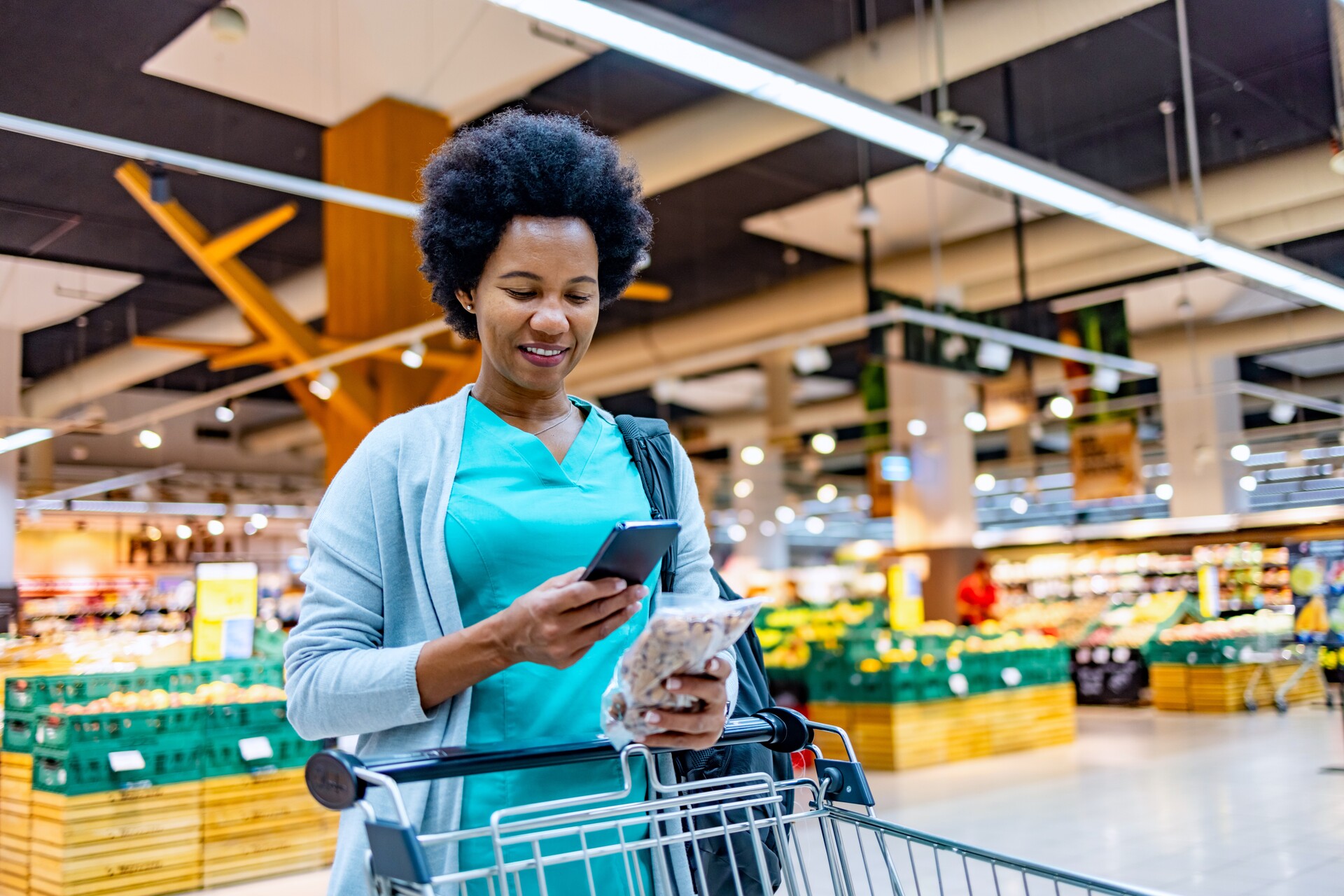 Frau im Supermarkt schaut auf ihr Handy